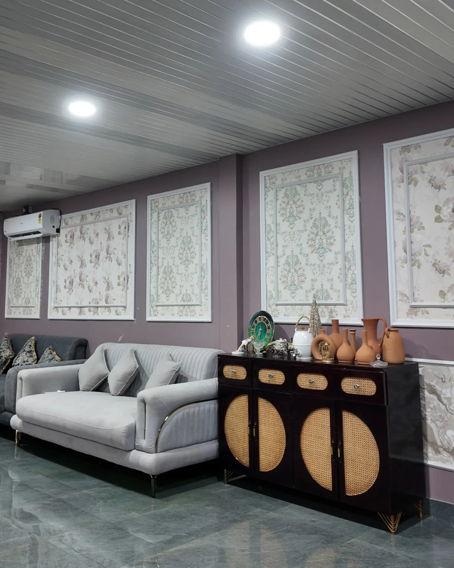 Lounge with floral wall panels, a grey sofa and a cane-front sideboard